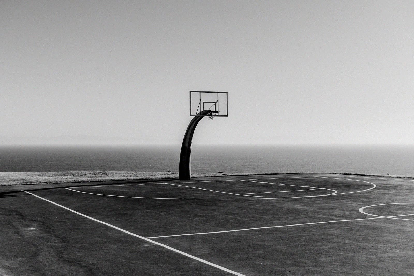 Outdoor basketball hoop overlooking the sea in gray morning light